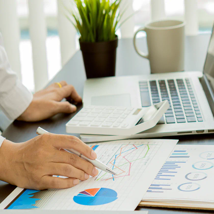 Profissional analisando indicadores e métricas em documentos impressos.